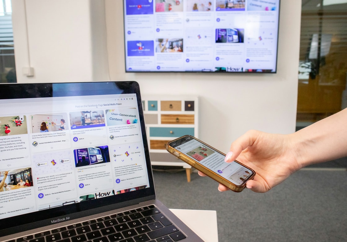 A person holding a phone in front of a laptop